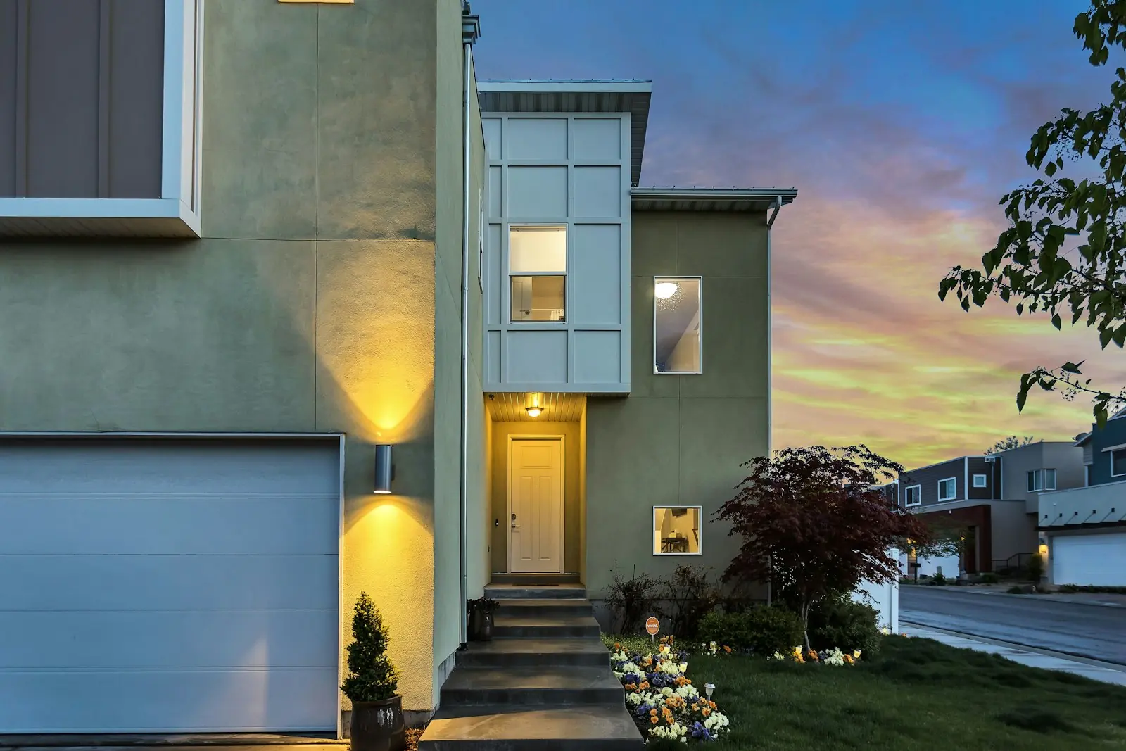 A house at dusk with the porch light on under a colourful sky