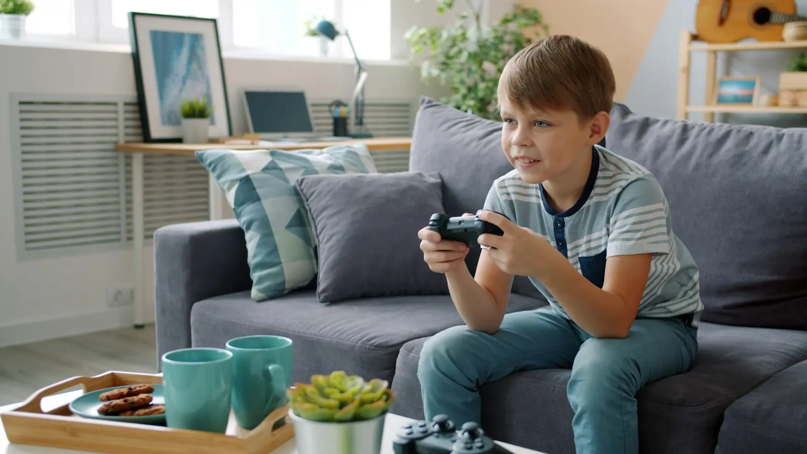 A boy on a grey sofa playing a video game