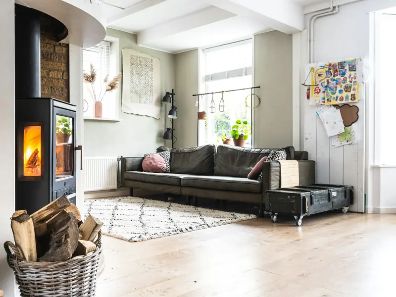 A warm living room with a wood burner, a radiator under the window and a sofa