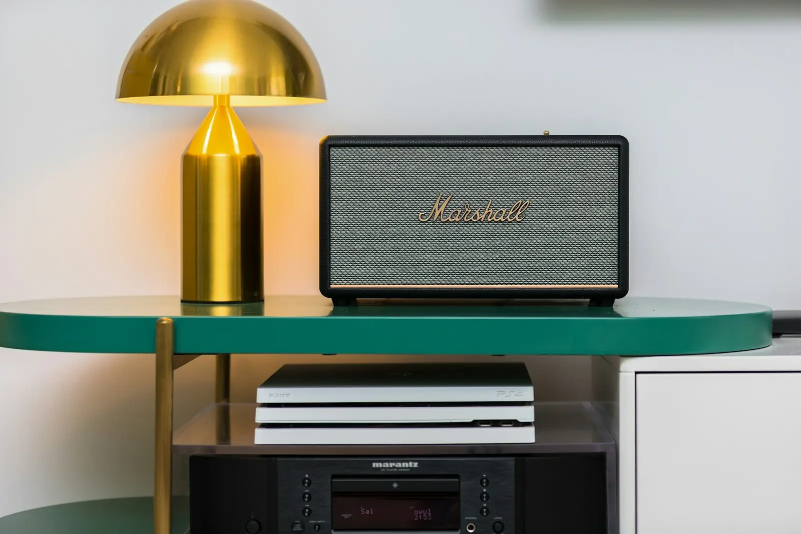 A speaker on a shelf beside a gold lamp