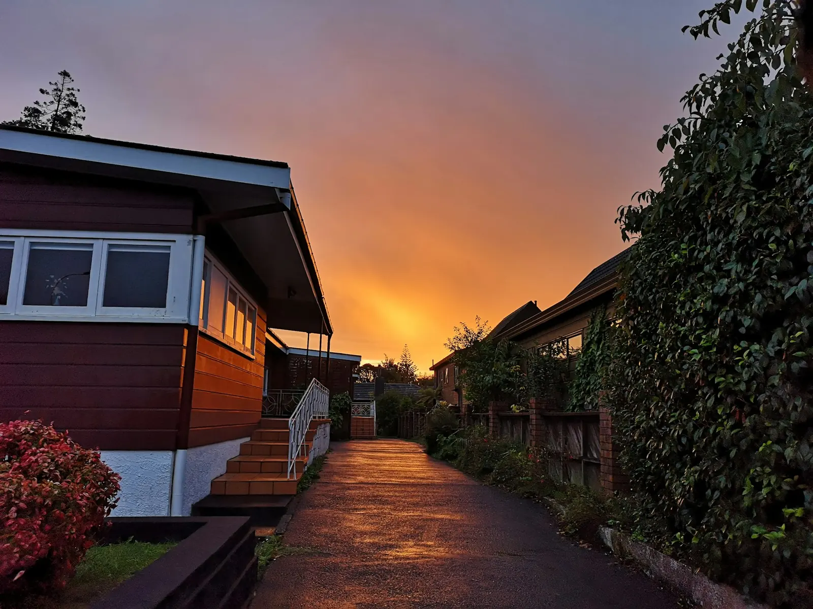 A row of houses at sunset, an orange sky glowing at the end of the street