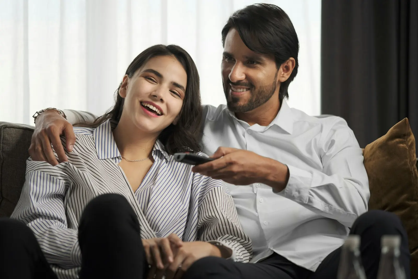 A couple laughing on the sofa with the TV remote